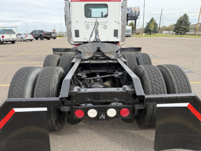 Kenworth T880 conventional daycab rear chassis showing dual rear axles and fifth wheel, metal frame, mud flaps and rear lights.
