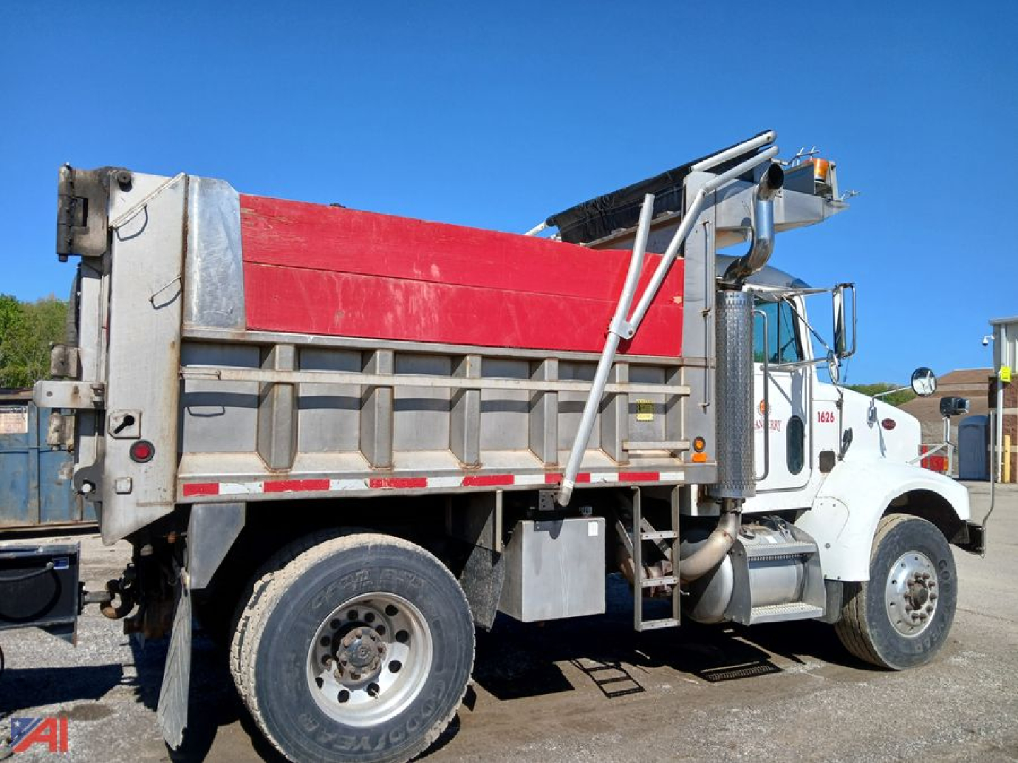 Peterbilt 330 dump truck side view showing red dump body and white cab, hydraulic lift mechanism, and dual rear wheels.