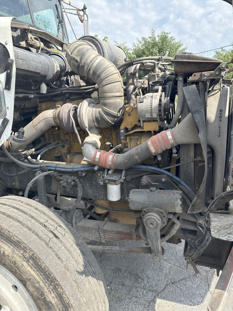 Kenworth T800 truck engine bay with exposed hoses, air intake, and mechanical components visible in front; Diesel engine and surrounding piping clearly seen.