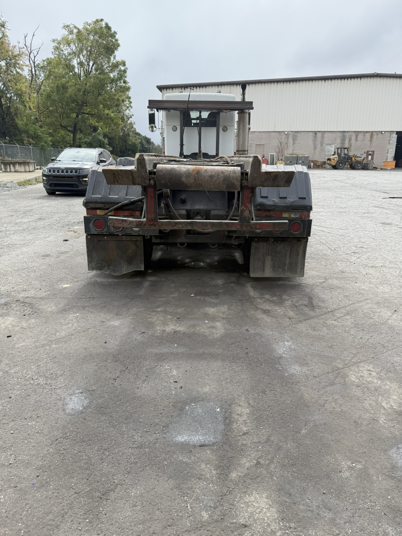 Kenworth T800 roll-off truck rear view showing dump bed hooks and bumper with mud flaps.