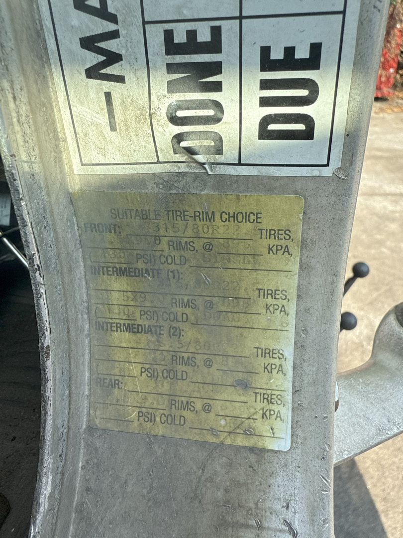 UPC label on Kenworth T800 rollover truck showing tire-rim choice chart with weights and pressures faded; VIN plate area visible.