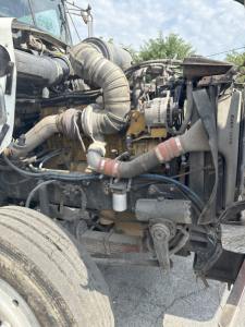 Kenworth T800 truck engine bay with exposed hoses, air intake, and mechanical components visible in front; Diesel engine and surrounding piping clearly seen.