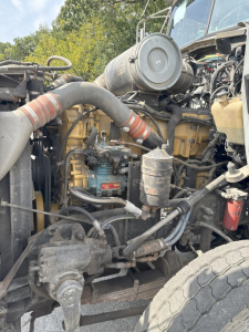 Kenworth T800 truck engine bay with hoses, hoses clamps, and hydraulic components visible; engine block, belts, and intake coupling in view.