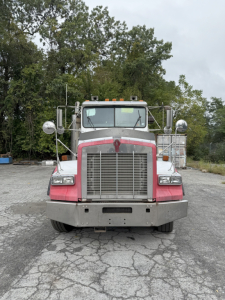 Front view of a Kenworth truck with large grille, bumper, and tall mirrors. No visible text legible on the cab or bumper.