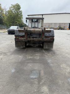 Kenworth T800 roll-off truck rear view showing dump bed hooks and bumper with mud flaps.