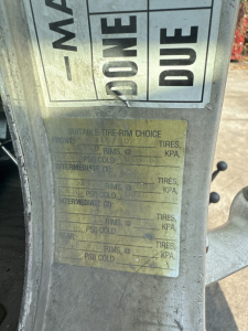 UPC label on Kenworth T800 rollover truck showing tire-rim choice chart with weights and pressures faded; VIN plate area visible.