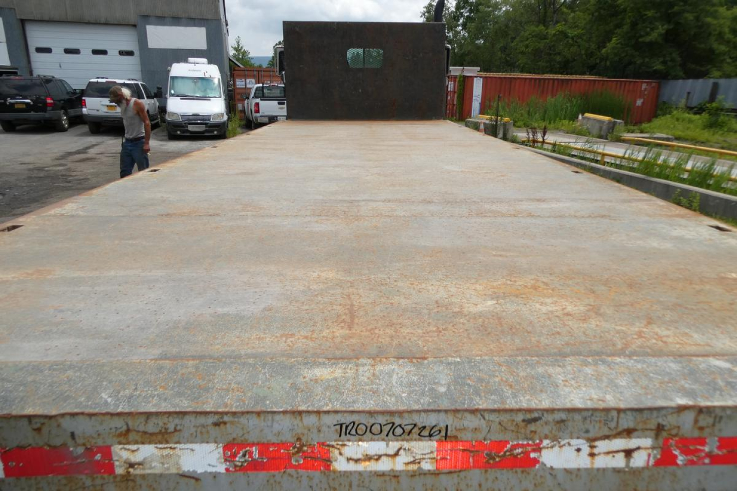Flatbed truck bed of a 1997 Mack RD690S showing a weathered steel deck with a rear license plate area and some rust patterns.