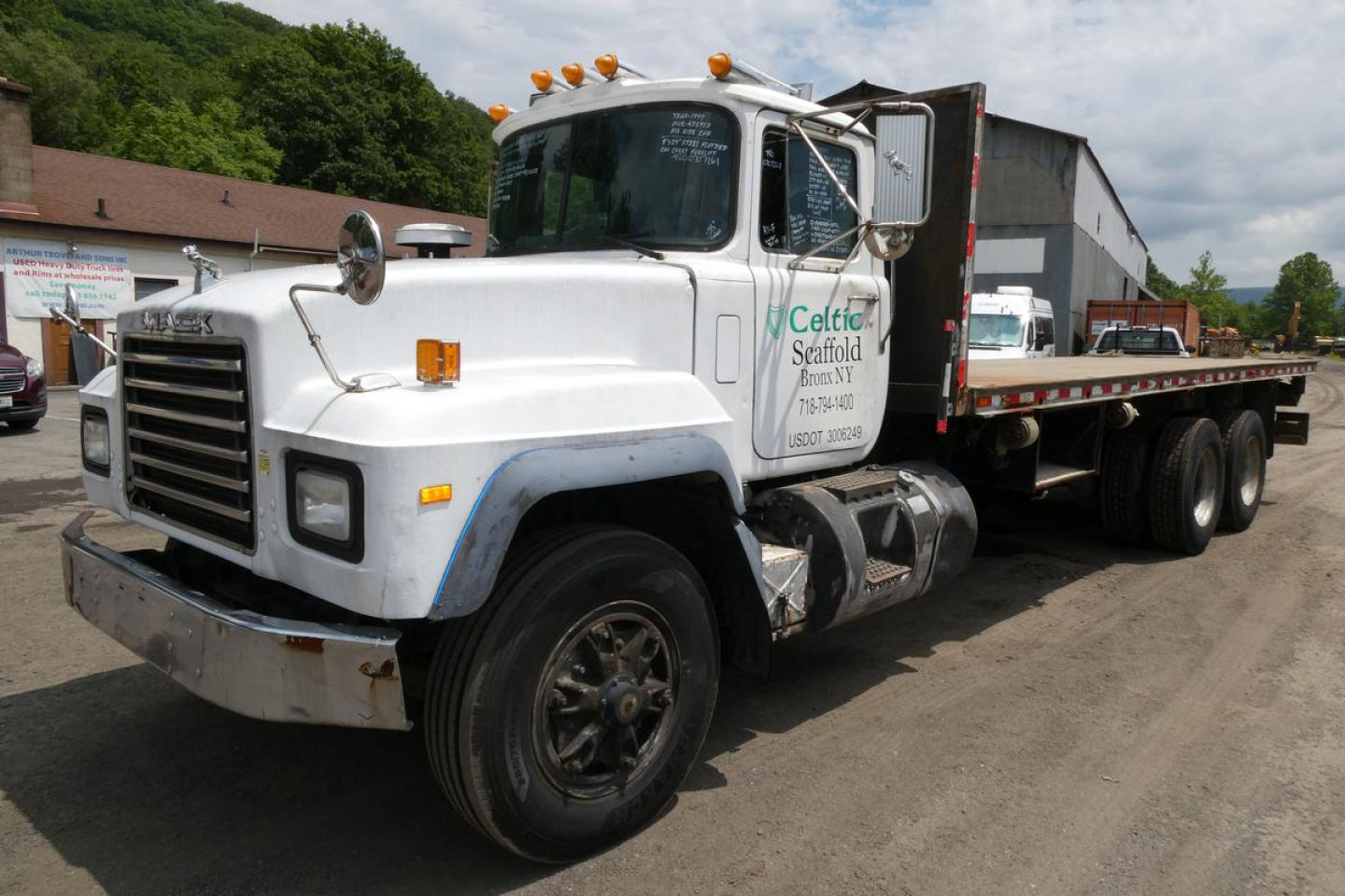 Mack RD690S flatbed truck showing cab side with Celtic Seaford sign and chrome bumper.