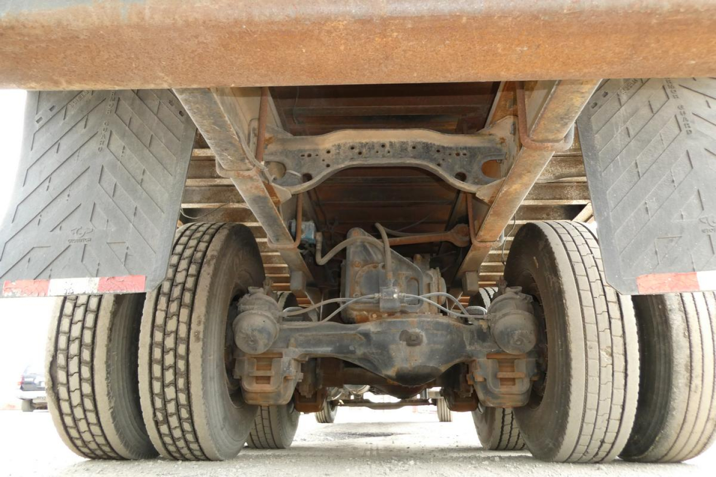 Rear view of a Mack RD690S truck showing dual rear axles and leaf spring suspension with drivetrain and differential visible under the flatbed.