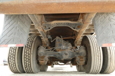 Rear view of a Mack RD690S truck showing dual rear axles and leaf spring suspension with drivetrain and differential visible under the flatbed.
