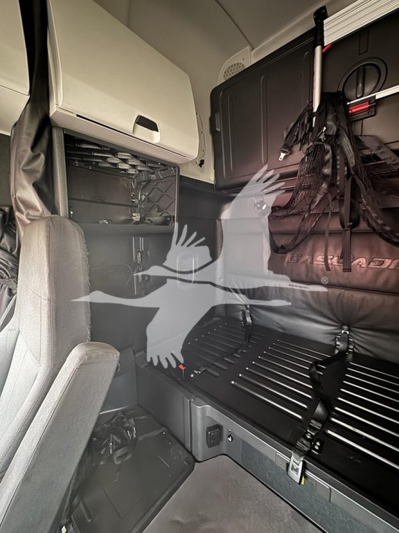 Truck cab interior showing sleeper area with storage compartments and overhead cabinetry in a Freightliner Cascadia 126.
