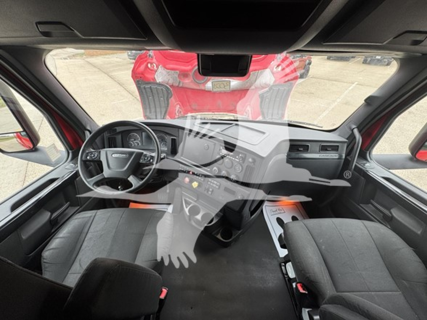 Cab interior of a Freightliner Cascadia truck showing steering wheel, dashboard, and front seats. Visible are instrument cluster, center console, and pedals.