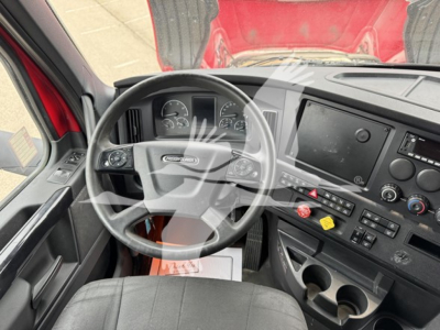 Cab interior of a 2023 Freightliner Cascadia 126 showing steering wheel, dashboard with large touchscreen, gauges, gear controls, and center console.
