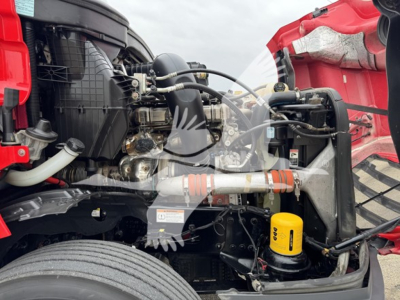 Freightliner Cascadia 126 engine bay view showing yellow engine oil filter and various hoses and components.