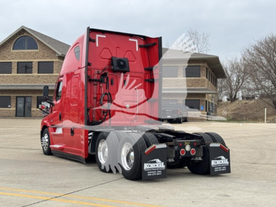 Freightliner Cascadia 126 tractor in red color, side view showing rear wheels and chassis with mud flaps and bumper area.