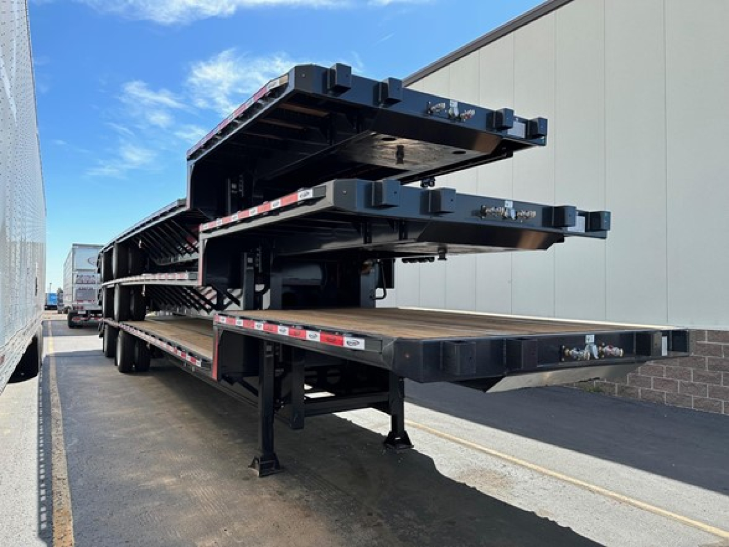 Trailer stack showing multiple steel drop deck sections with Beaver tail in a yard.