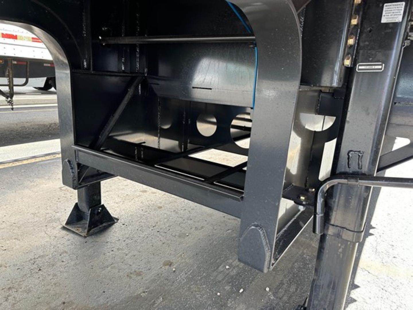 Trailer undercarriage with steel drop deck and beaver tail showing structural frame and support brackets.