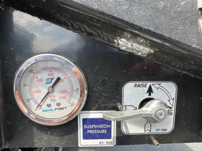 Trailer dashboard showing a round pressure gauge and suspension pressure label with a pull handle and control sticker.