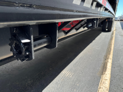 Drop deck trailer undercarriage showing hitch/kingpin area with black steel frame and underside components.