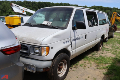 Ford E-Series cargo van side view showing MassBay van with open passenger door and a dented front, white color, in a lot.