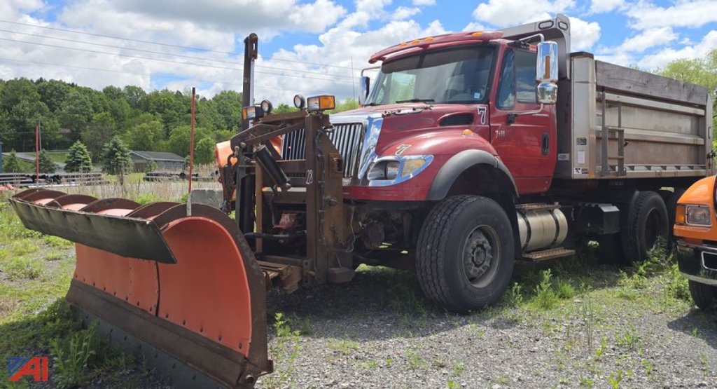 Dump truck with plow and snow removal blade, red International WorkStar 7600, side dump bed, front mounted snow plow, heavy-duty tires, daytime outdoor lot
