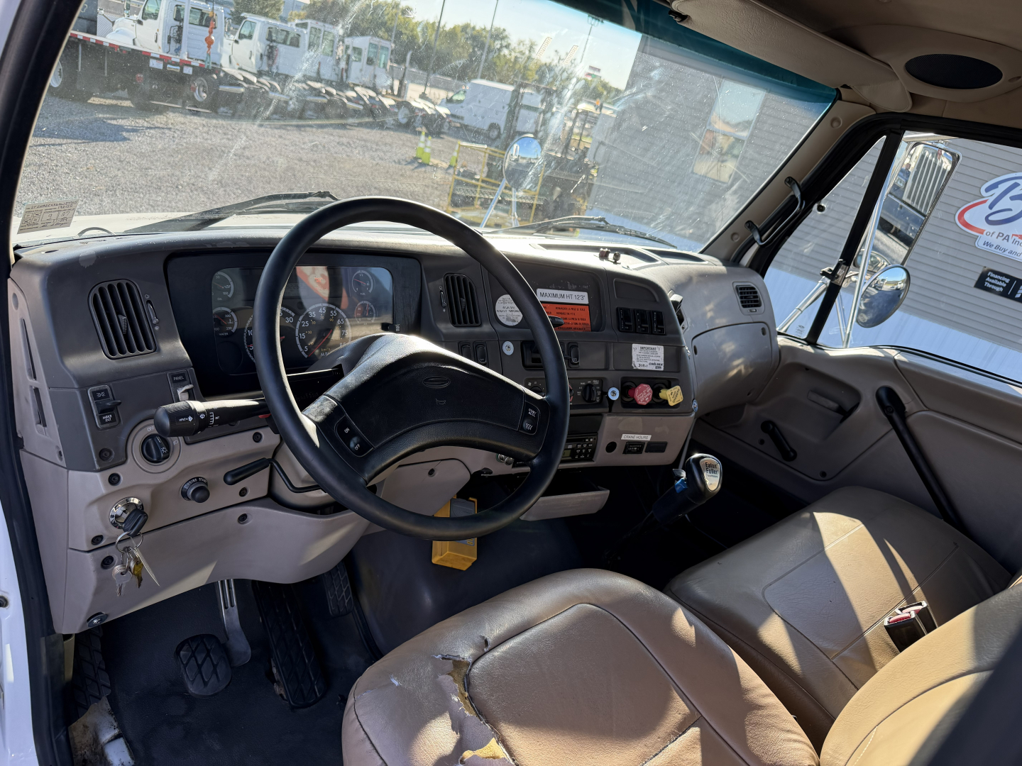 Truck cab interior of a 2006 Sterling LT9500 showing steering wheel, dashboard, and driver seat from passenger side; visible gauges, controls, and gear shifter.