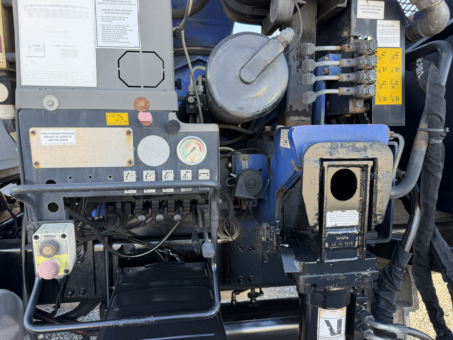 Sterling LT9500 truck engine bay showing hydraulic boom controls and multiple warning labels. Visible components include gauges, wiring, and blue and black metal housings.