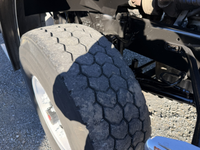 Vehicle wheel and front suspension of a 2006 Sterling LT9500 boom truck showing the front tire tread and part of the axle assembly.
