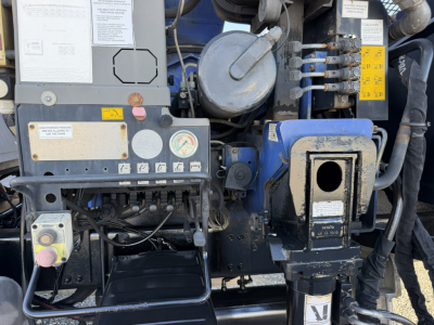 Sterling LT9500 truck engine bay showing hydraulic boom controls and multiple warning labels. Visible components include gauges, wiring, and blue and black metal housings.