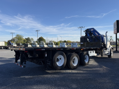 Flatbed truck trailer with black frame and triple rear axles, Sterling LT9500 with crane at cab side, used vehicle for sale.