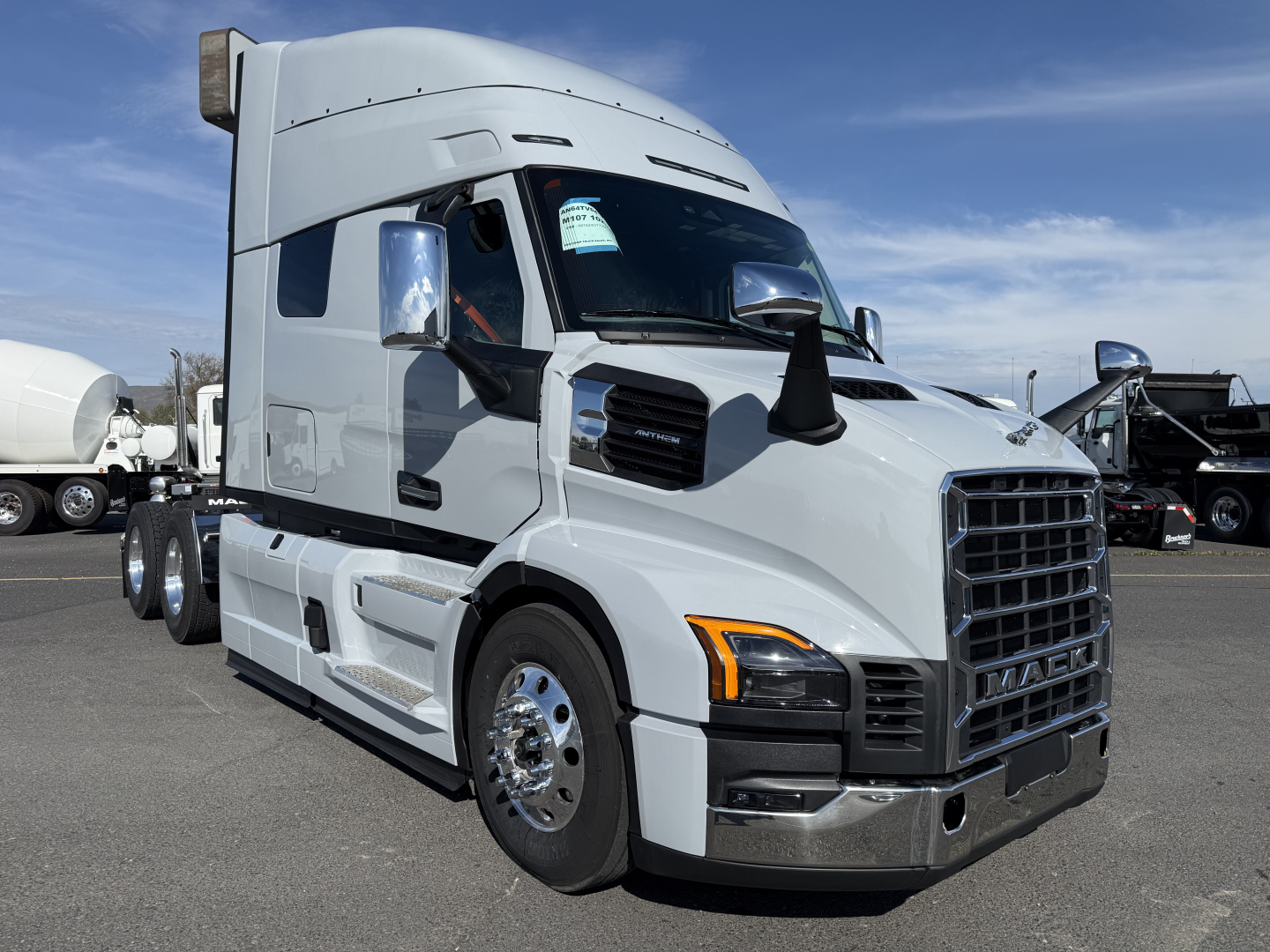 Truck exterior showing Mack AN64T64 sleeper tractor with chrome grille and mirror caps, silver/gray paint, side fuel tanks, and three rear axles.