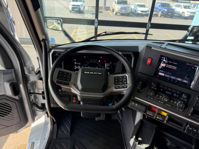 Mack AN64T64 truck cabin interior with steering wheel and dashboard controls; view from driver seat showing instrument cluster and infotainment screen.