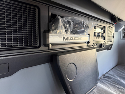 Mack AN64T64 truck cabin interior with dashboard controls and a packaged component labeled ‘MACK’ visible.