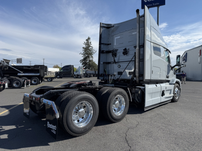 Truck: Mack AN64T64 conventional sleeper tractor, side view with three-axle rear and dual rear tires, silver cab, chrome wheels, blank trailing equipment, parking lot.