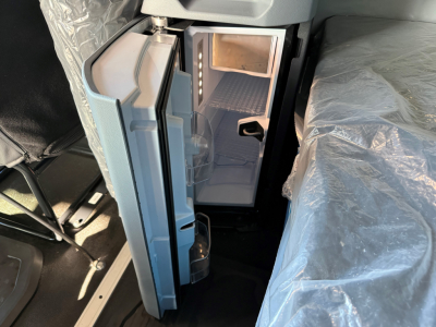 Open refrigerator in a Mack AN64T64 truck cab showing empty interior and small freezer area.