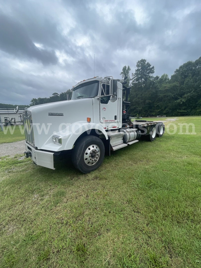Kenworth T800 semi truck in profile view showing white cab, dual rear axles, and long chassis with fuel tanks and steps.