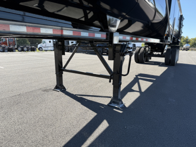 Trailer landing gear and side frame of a 2027 Armor Lite dump trailer showing structural legs and supports.