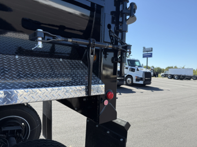 Armor Lite dump trailer rear corner showing diamond plate fender and taillight, black paint, and rear bumper.