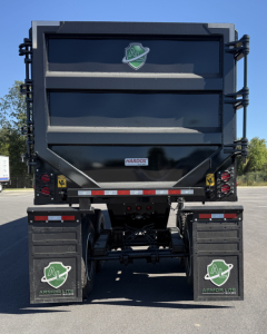 Dump trailer rear view showing Armor Lite branding and mudflaps with green shield logo; dual axles, rear underride guards, and Hardox label on the tailgate.