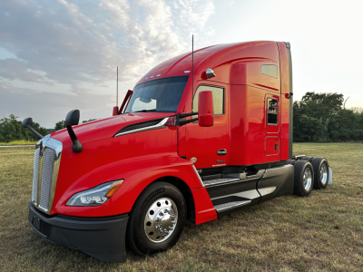 Kenworth T680 tractor in red color, side view showing cab and dual rear axles.