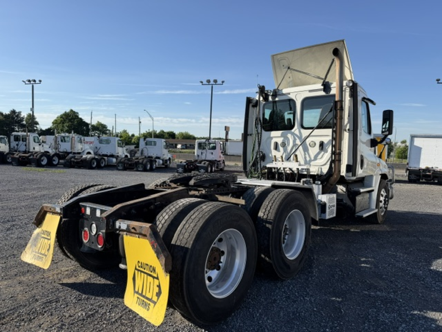Freightliner Cascadia 125DC tractor truck side view showing rear wheel duals, fifth wheel, and cab with raised hood; warning flags behind rear wheels.