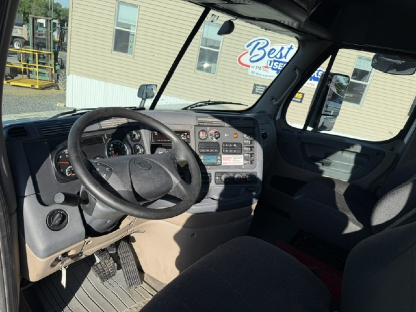 Cab interior of a Freightliner Cascadia Daycab showing steering wheel, dashboard with gauges, radio, and controls