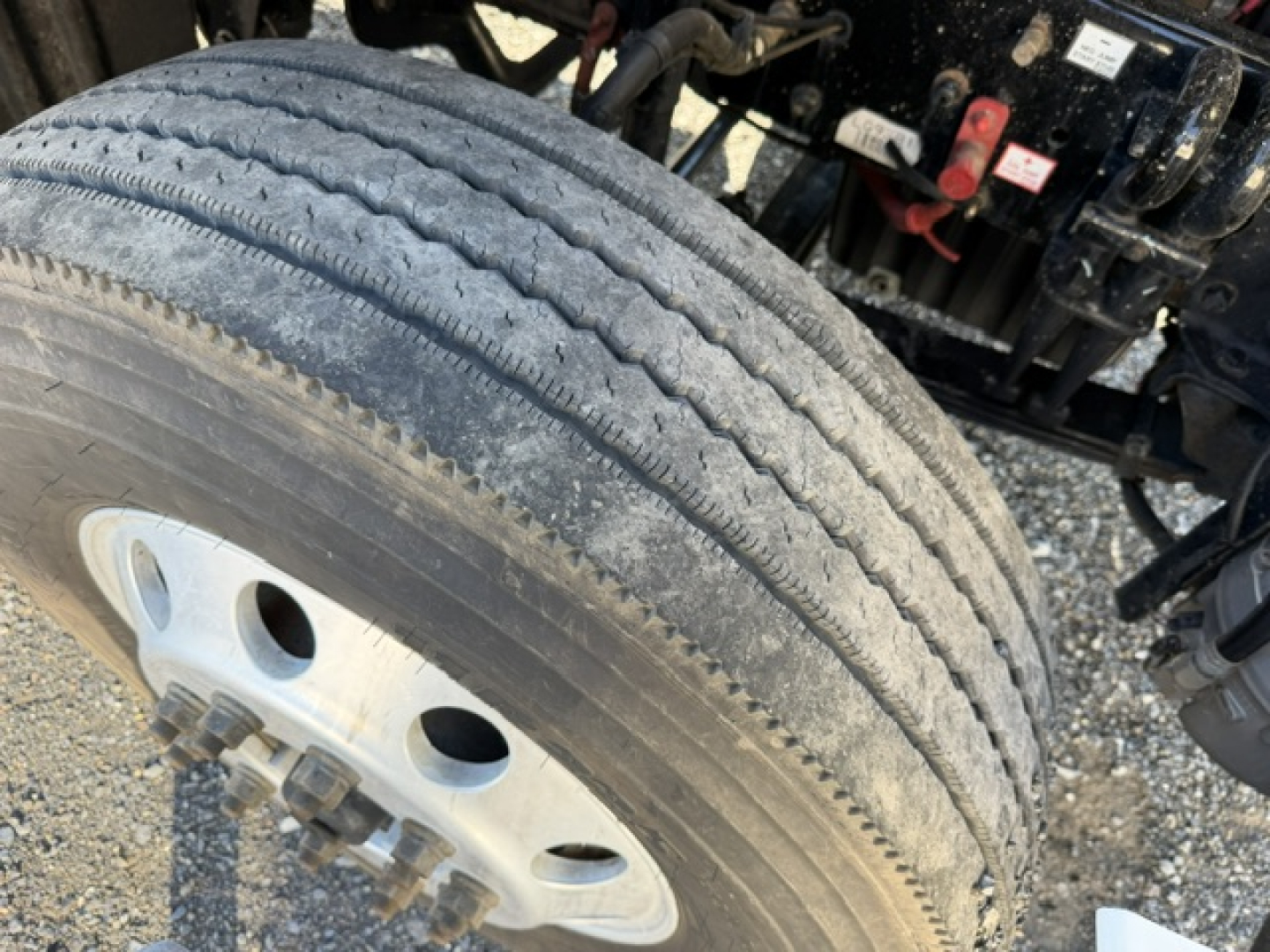 Truck wheel and dual tire setup with a partial view of Freightliner Cascadia front suspension and frame.