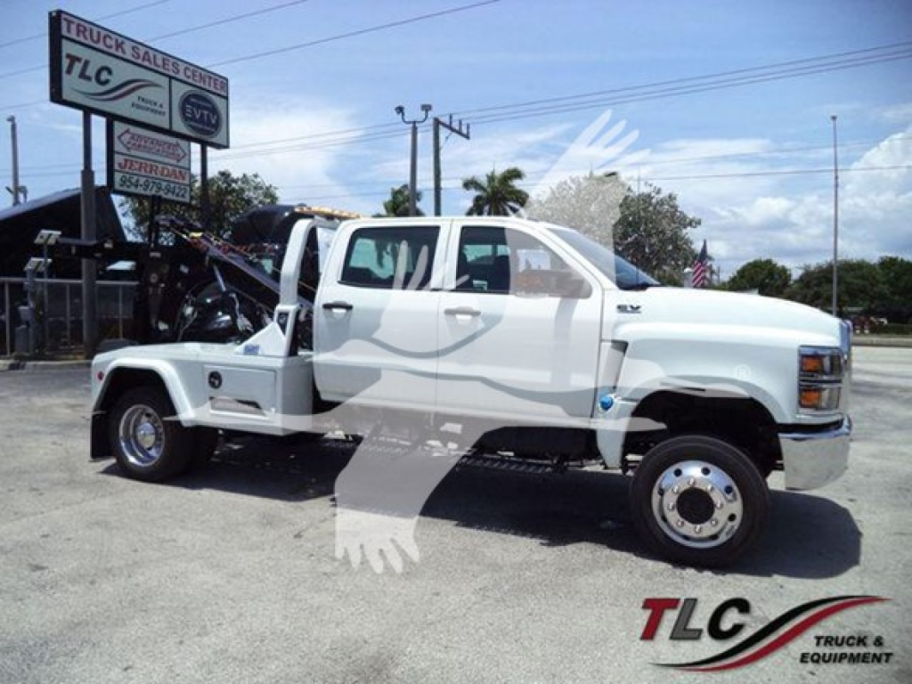 Truck bay showing a white 2023 International CV medium-duty with a tow winch and taglines, VIN 1HTKTSWK3PH419799, stock J19799, in a dealership lot.