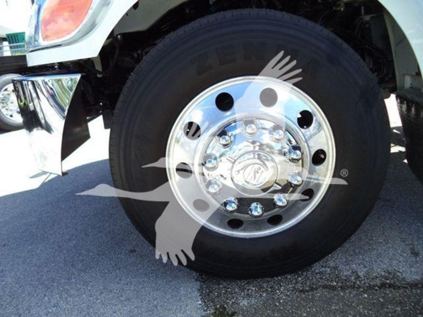 Peterbilt 337 front wheel showing chrome hub with lug nuts and outer tire, partial fender and bumper visible.