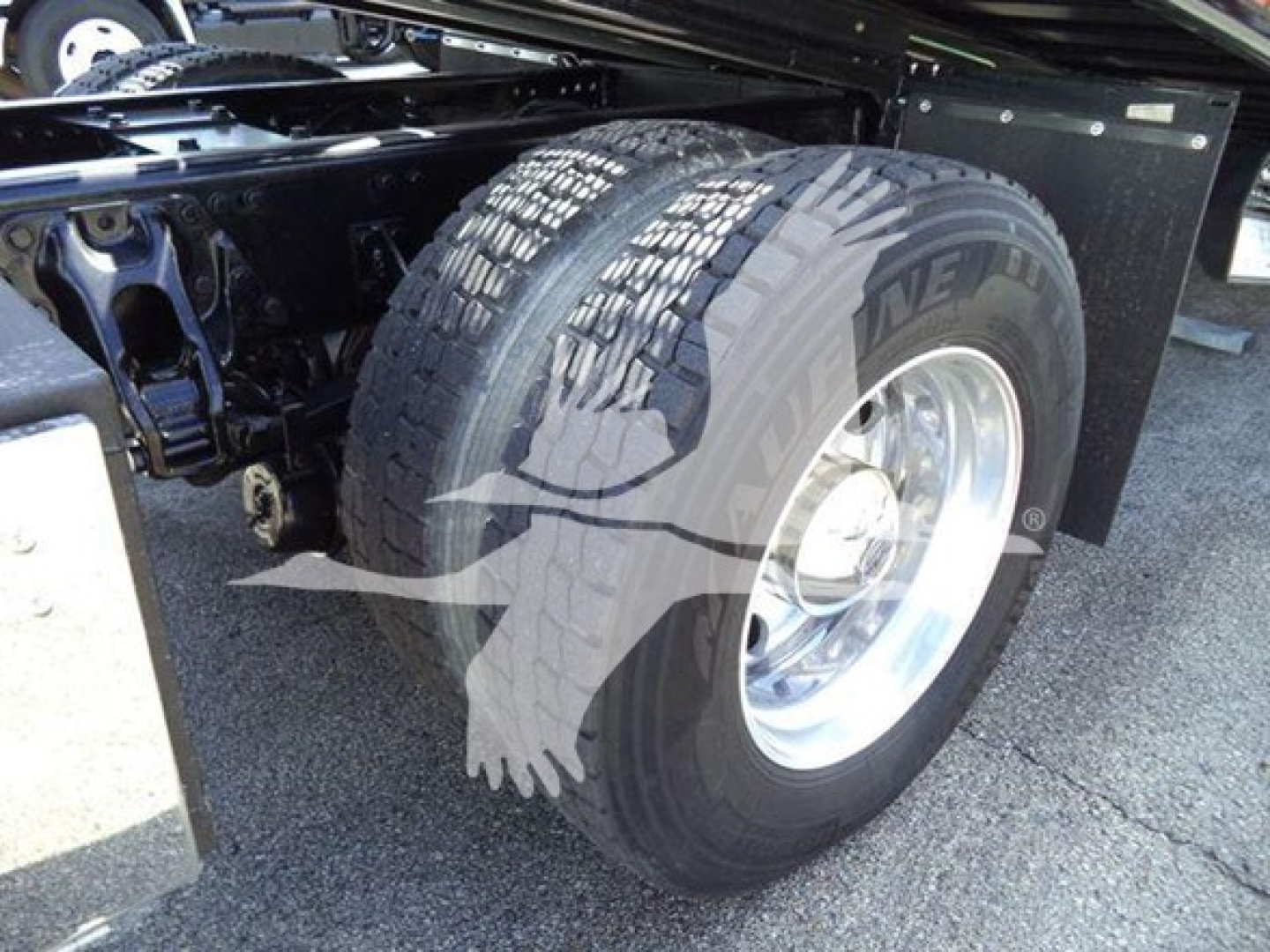 Peterbilt 337 rollback truck rear wheel and suspension showing tire with tread and chrome wheel.