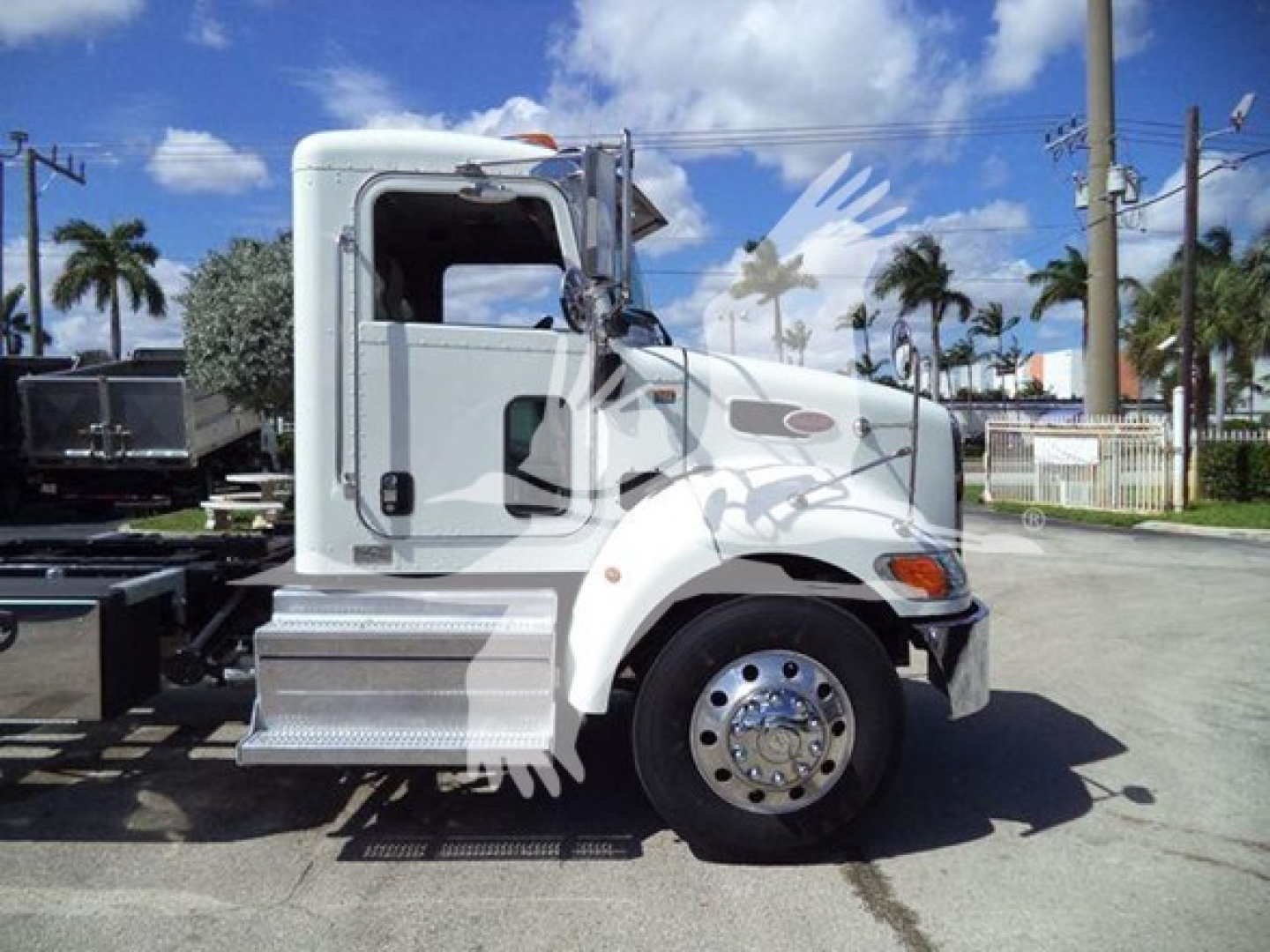 Peterbilt 337 roll-back truck side view showing cab and front wheel, white paint, chrome hubcap, side steps, and fuel/airline components.