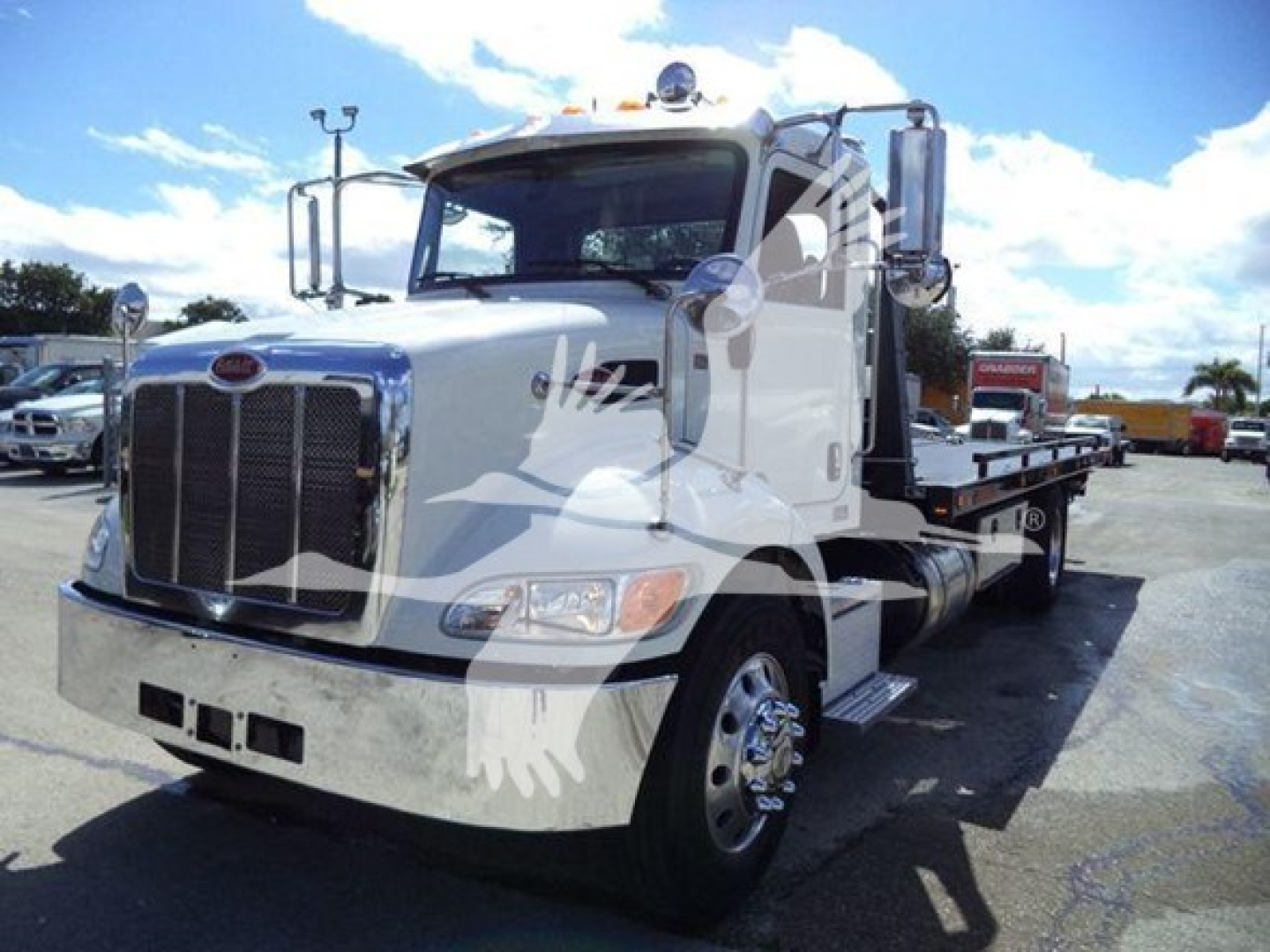Peterbilt 337 rollback tow truck in a used inventory photo, front grille, side deck, dual mirrors and chrome wheels visible.