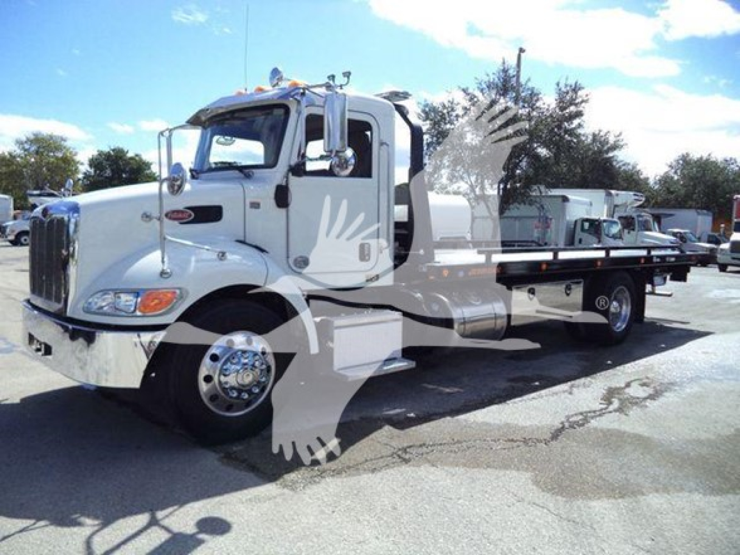 Peterbilt 337 rollback tow truck side view showing white cab and flatbed, chrome bumper, dual rear axles, and hydraulic equipment.