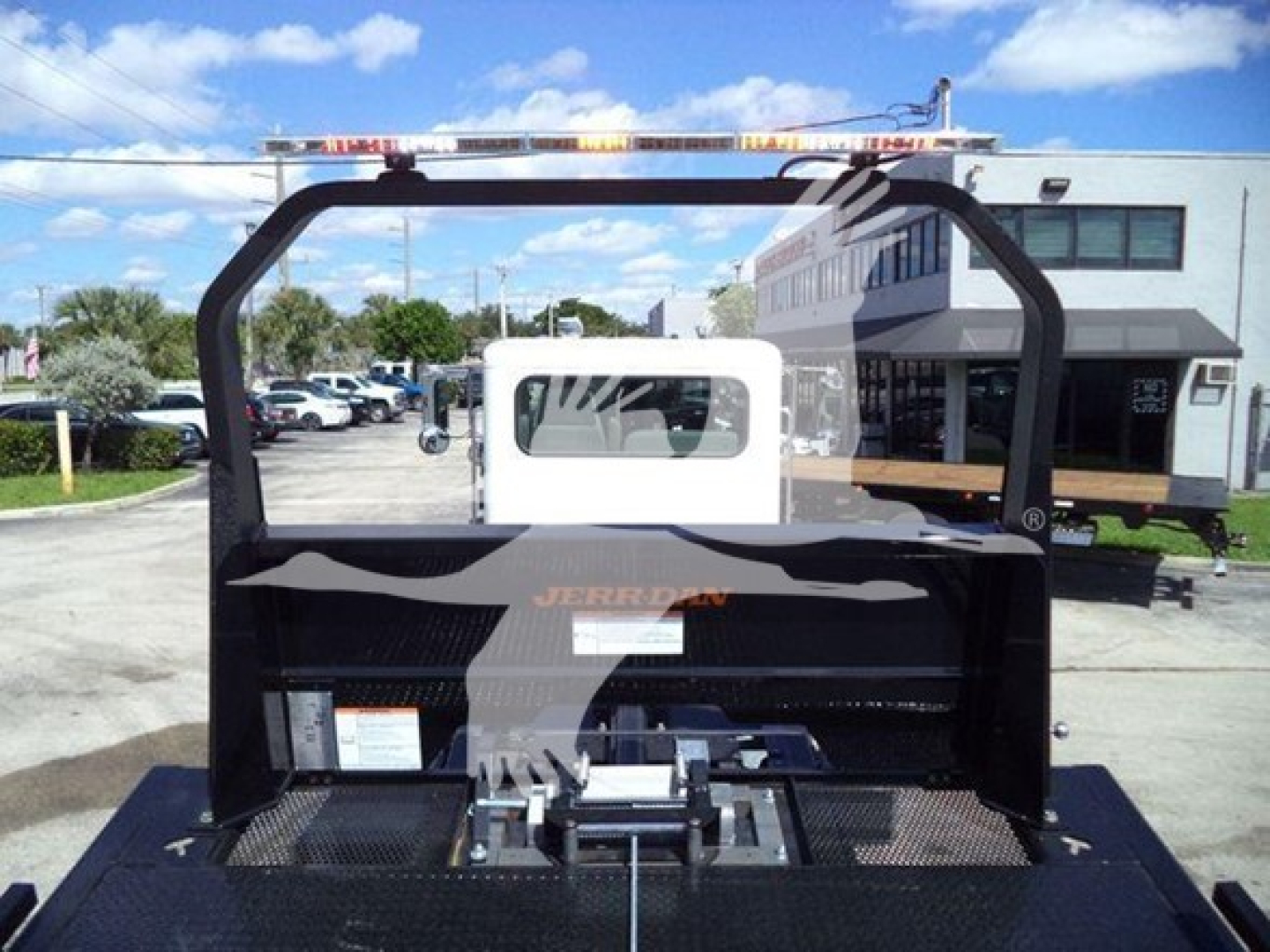 Peterbilt rollback truck bed with black frame and white cab behind, showing mounting hardware and steel decking.